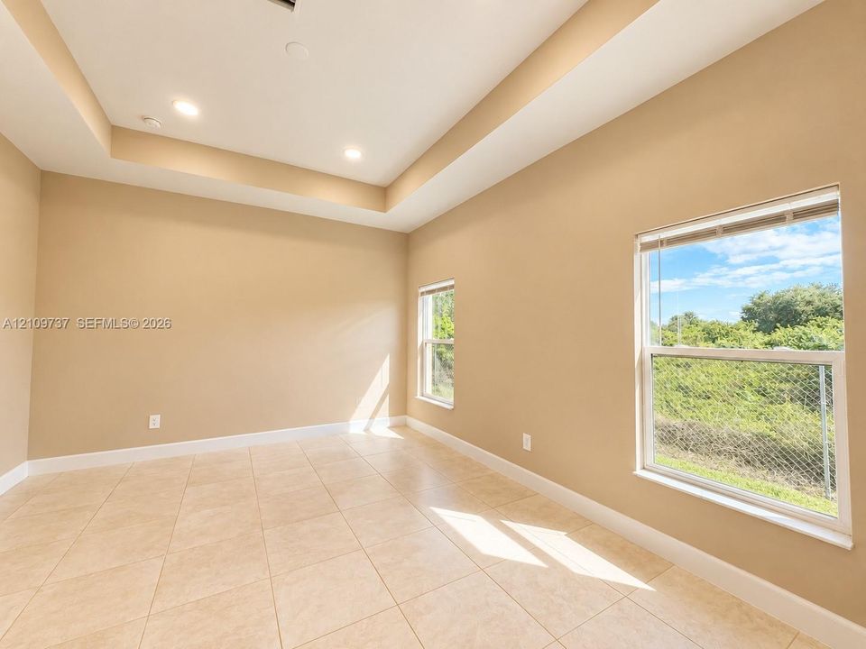 Room featuring a tray ceiling, recessed lighting, tile flooring, and dual windows