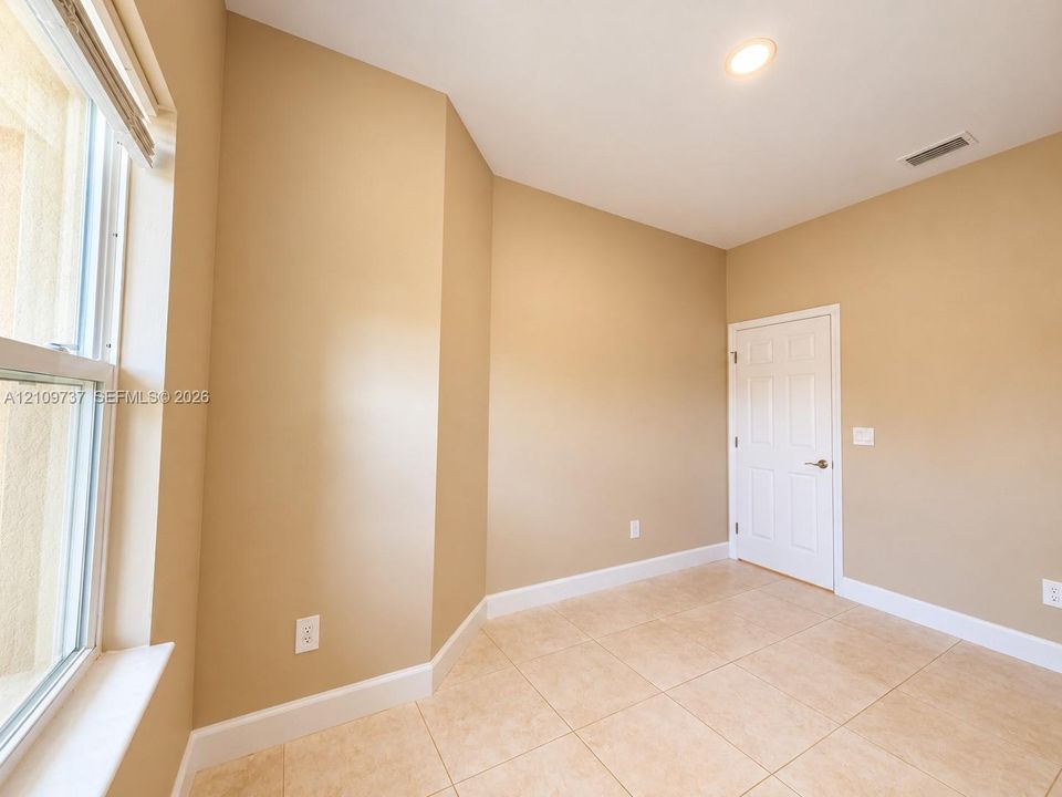 Neutral-toned interior featuring ceramic tile flooring, recessed ceiling lighting, a multi-panel door, and a single-hung window with a sill