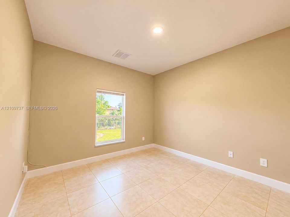 Neutral-toned room featuring large-format ceramic tile flooring, a recessed ceiling light, and a single-pane window