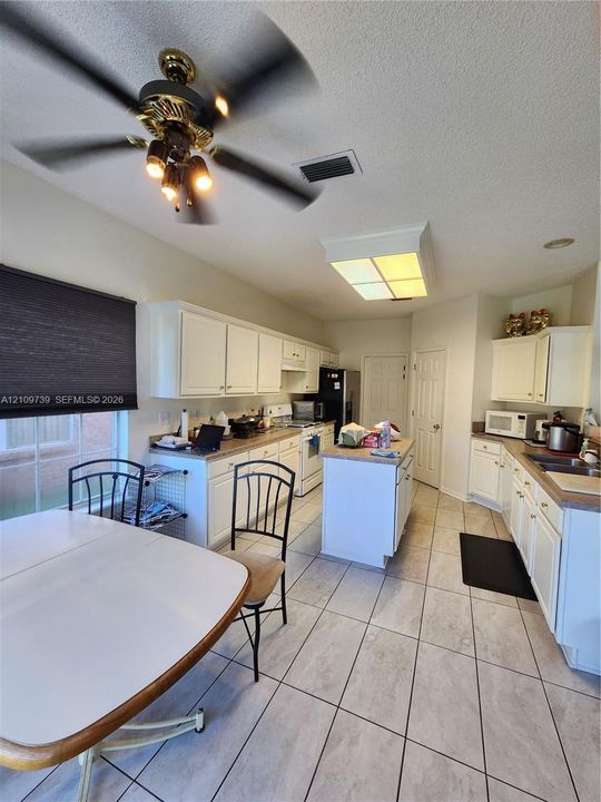 Kitchen featuring white cabinetry, center island, tile flooring, and integrated ceiling lighting