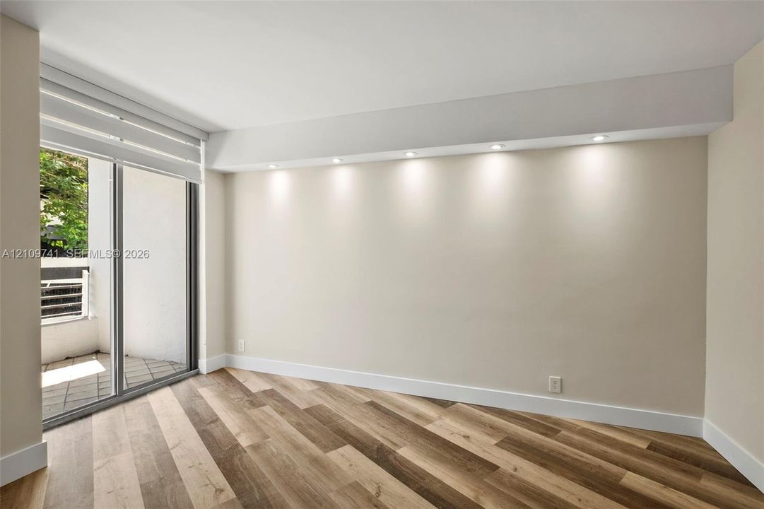 Wood-finish flooring, recessed soffit lighting, and sliding glass door with access to a private balcony
