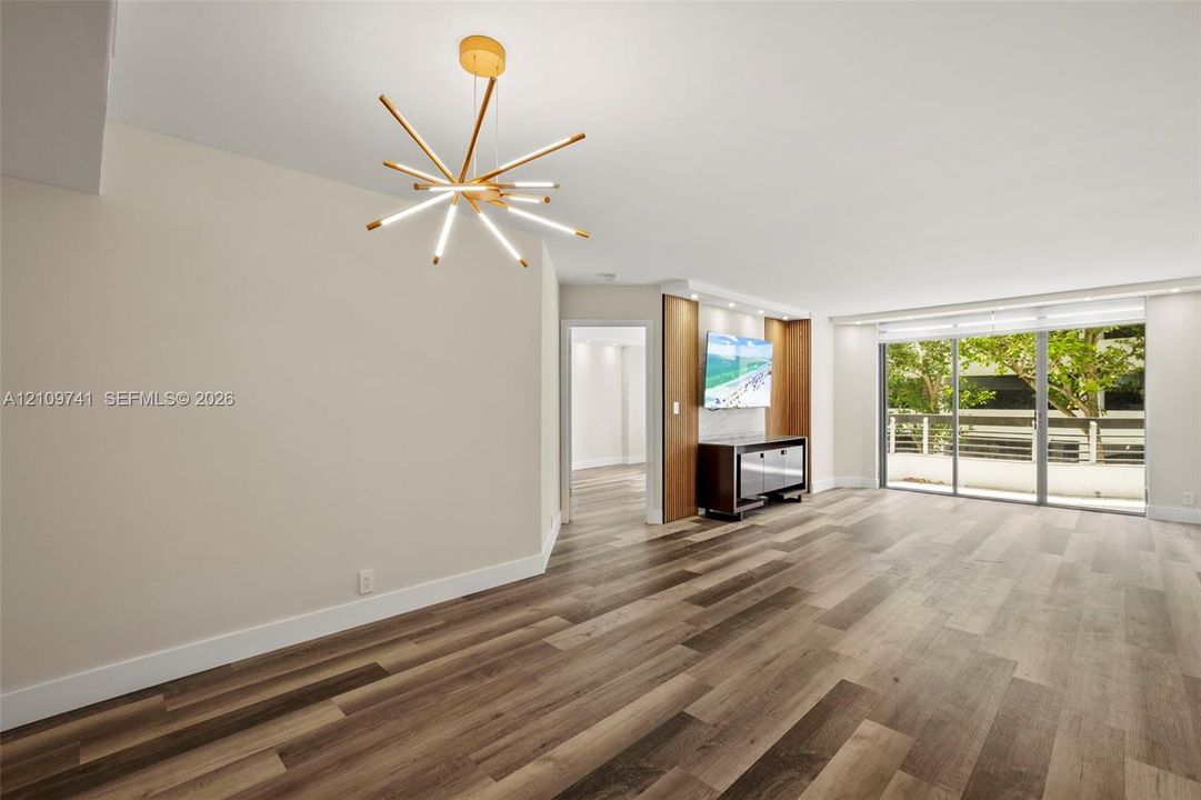Wood-finish flooring, multi-arm contemporary pendant light, custom built-in cabinetry with integrated accent lighting, and expansive sliding glass doors