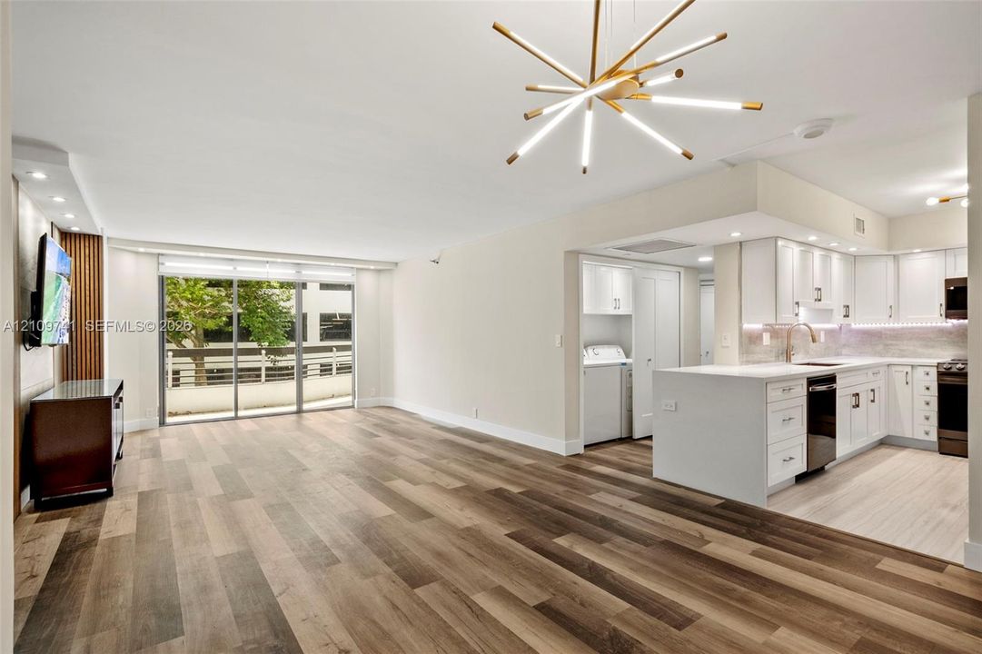 Open-concept area featuring wood-finish flooring, a modern sputnik-style chandelier, and floor-to-ceiling sliding glass doors