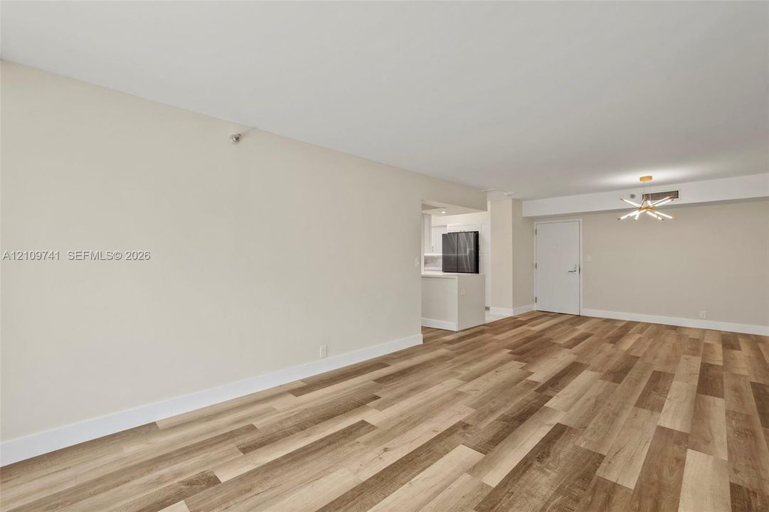 Open-concept interior featuring wood-finish plank flooring, neutral wall tones, and a modern sputnik-style chandelier