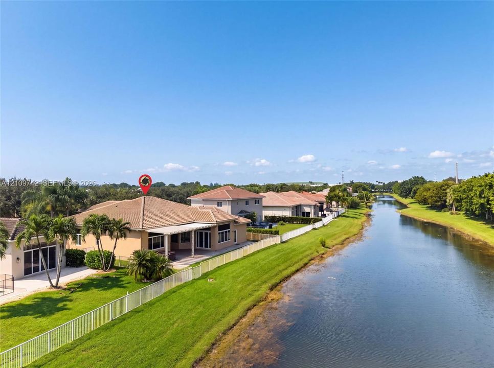 Waterfront property featuring a covered patio, tile roof, and perimeter fencing along a canal