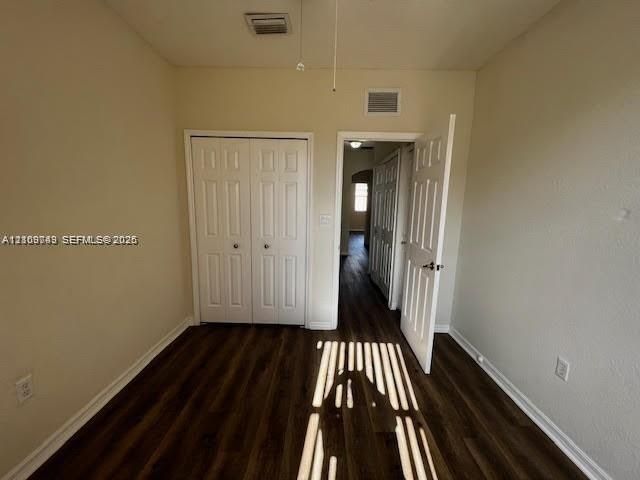 Interior space featuring wood-finish flooring, white panel closet doors, a neutral wall finish, and a white interior swing door