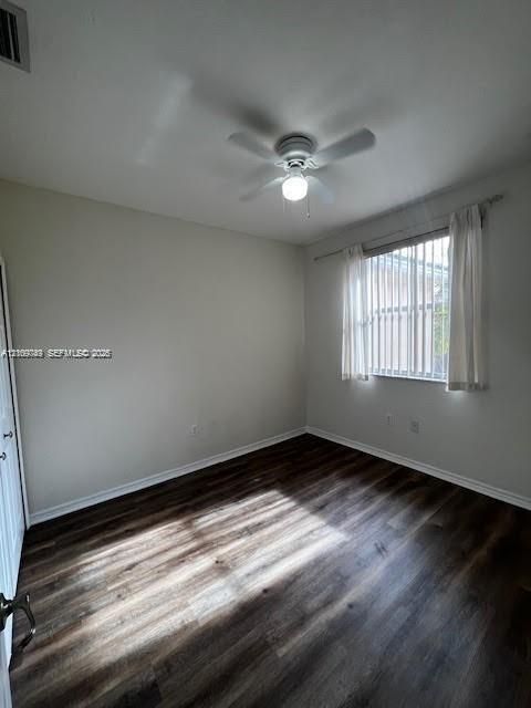 Neutral-toned interior featuring dark wood-finish flooring, a ceiling fan with integrated light fixture, and vertical window blinds