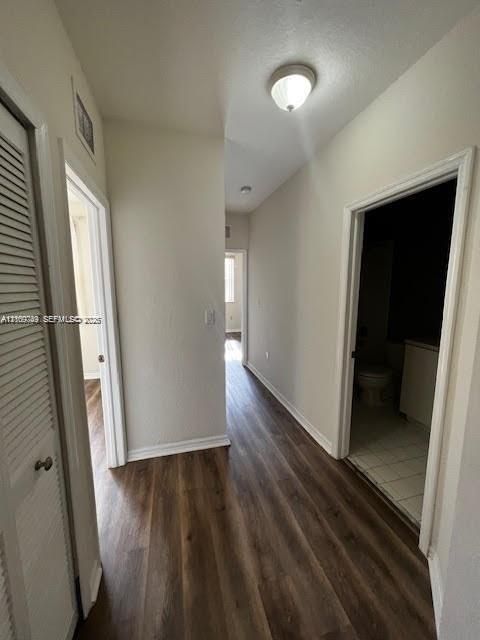 Interior hallway featuring wood-finish flooring, white door casings, and a ceiling-mounted dome light fixture