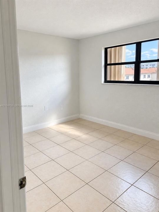Neutral wall finish, large-format ceramic tile flooring, and dark-framed window
