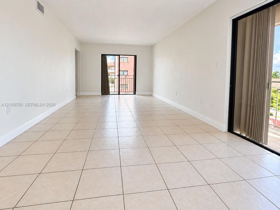 Neutral-toned ceramic tile flooring, expansive wall space, and dual sliding glass doors providing external exposure