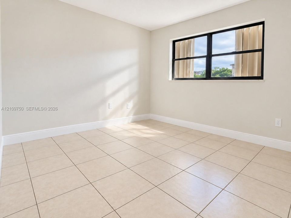 Neutral-toned interior space featuring light ceramic tile flooring, neutral wall paint, and a large horizontal window framed in matte black