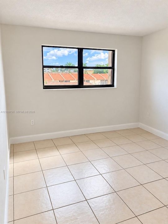 Neutral-toned interior space featuring light-colored floor tile, crisp painted walls, and a window with a black frame