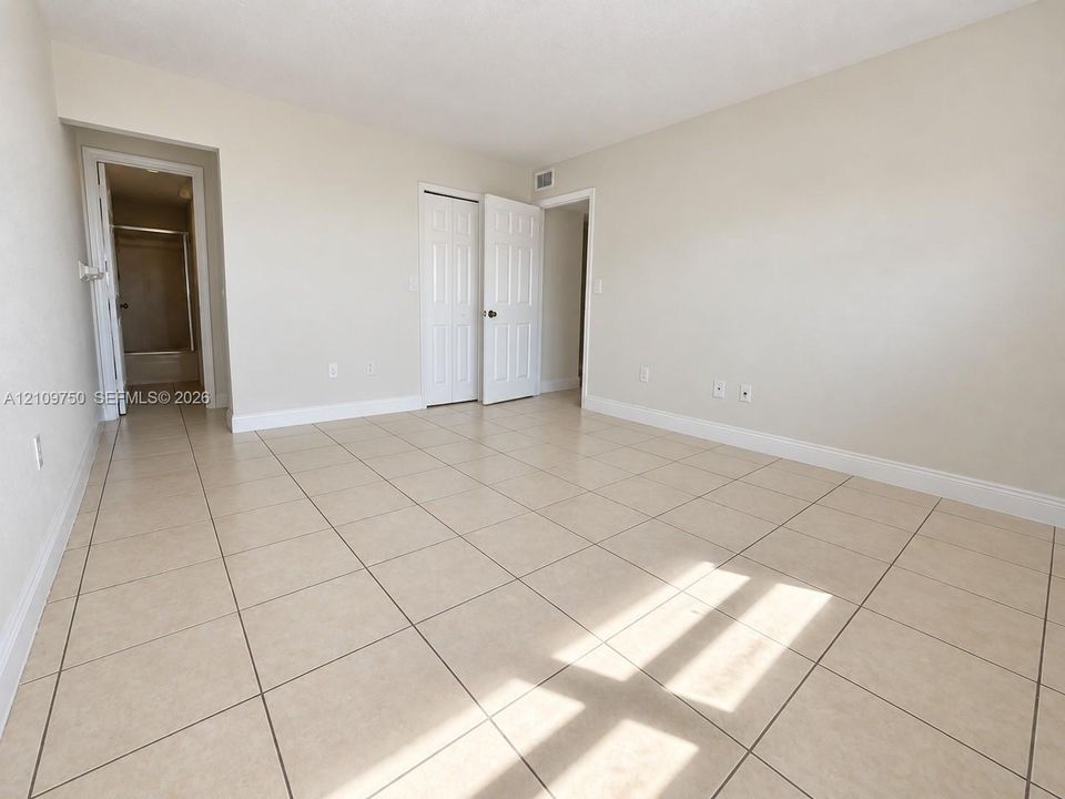 Neutral-toned interior featuring large-format ceramic tile flooring, multi-panel closet doors, and smooth wall finishes