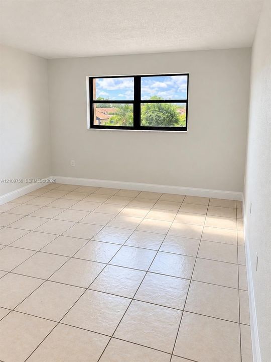 Neutral wall tones, ceramic tile flooring, and a window with black-framed casing