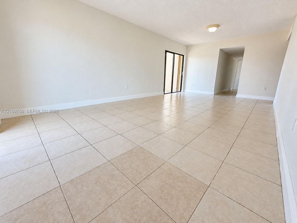 Neutral interior space featuring large-format ceramic tile flooring, neutral wall tones, a ceiling-mounted light fixture, and a glass sliding door