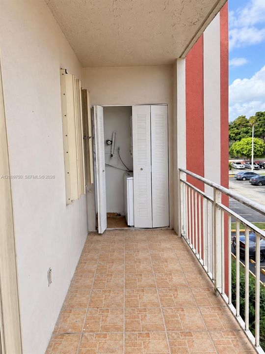 Covered balcony featuring tiled flooring, metal railing, and a dedicated laundry closet with louvered bi-fold doors