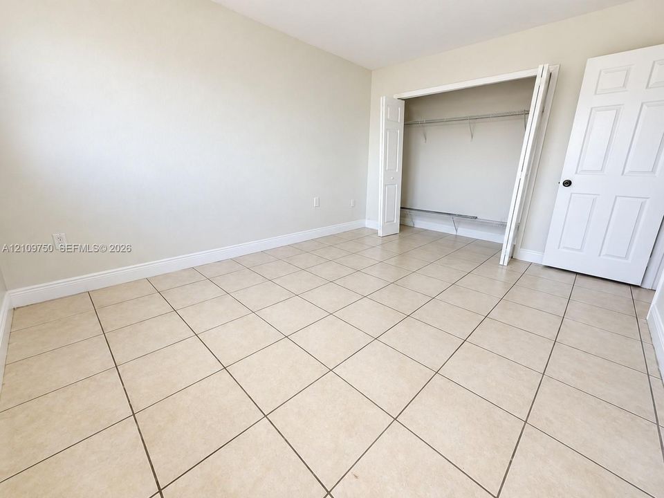 Neutral-toned ceramic tile flooring, neutral wall paint, closet with bi-fold doors, and a paneled interior door