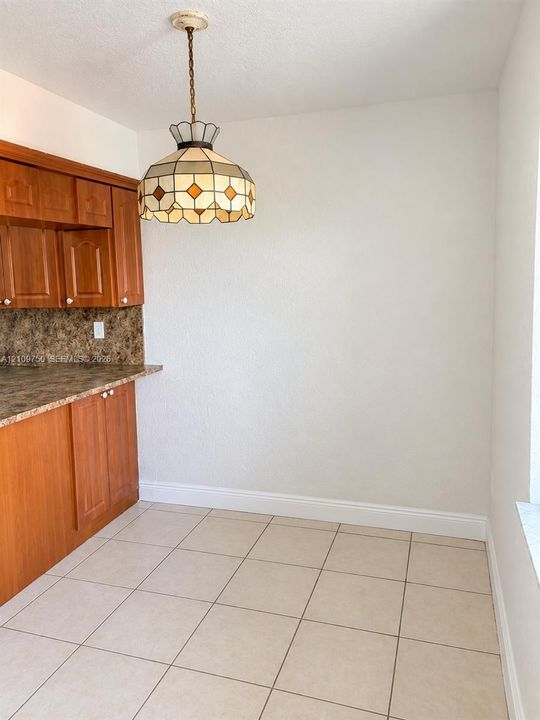 Stained wood cabinetry, patterned stone-finish countertops, geometric stained glass pendant lighting, and ceramic tile flooring