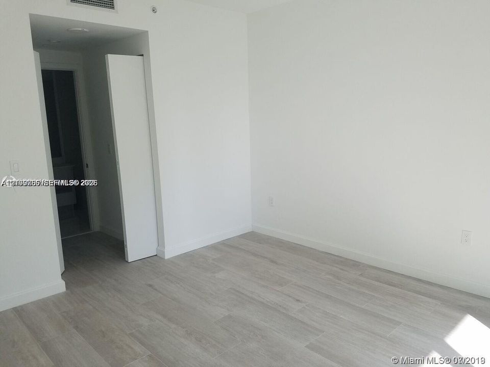 Neutral interior featuring wood-finish flooring, white walls, and a recessed ceiling lighting fixture