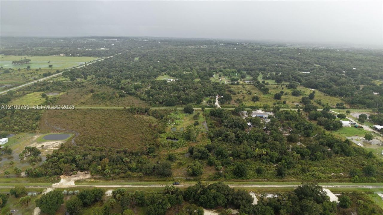 Aerial perspective of expansive acreage featuring mature tree canopy, cleared sections, and natural vegetation