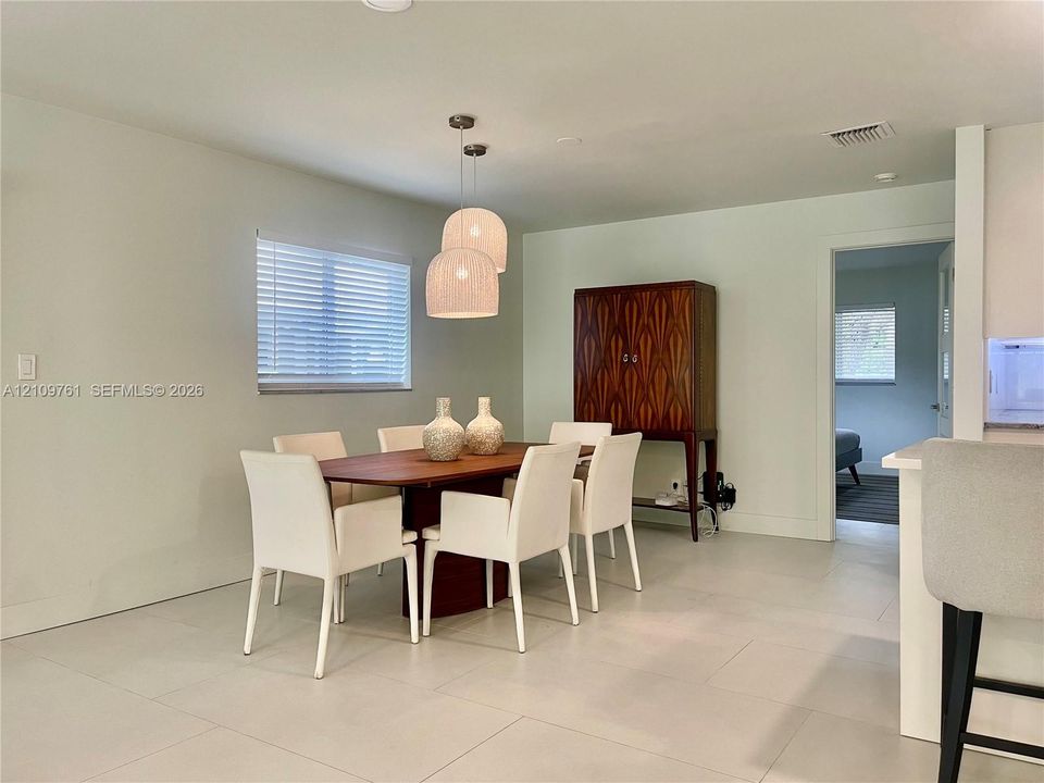 Neutral interior featuring large-format tile flooring, recessed lighting, double pendant lighting fixture, and horizontal blind window treatment