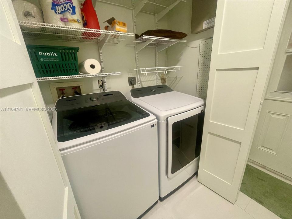 Laundry area featuring white cabinetry doors, multi-tier wire shelving, and a wall-mounted pegboard