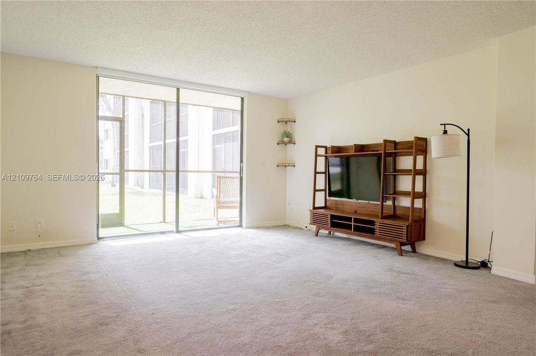 Neutral-toned living space featuring wall-to-wall carpeting and floor-to-ceiling sliding glass doors