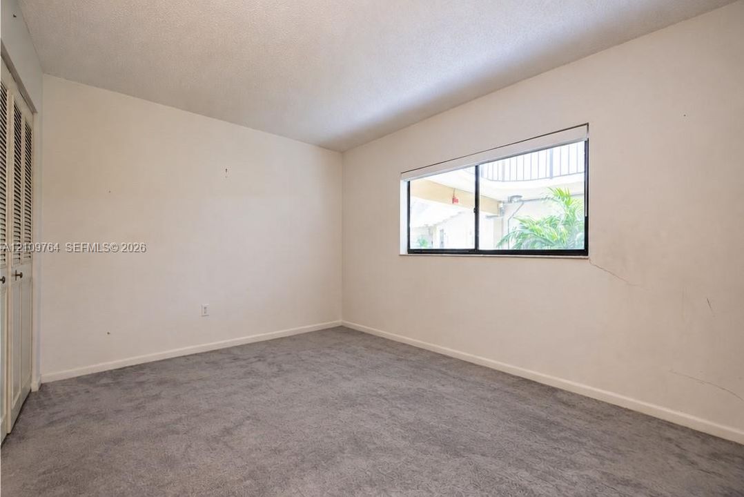Neutral-toned carpeted flooring, large window, and louvered closet doors