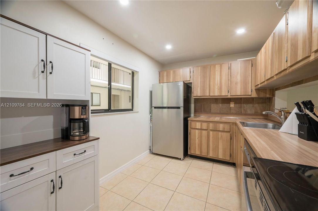 Kitchen featuring stainless steel appliances, wood-finish cabinetry, tile flooring, and solid-surface countertops
