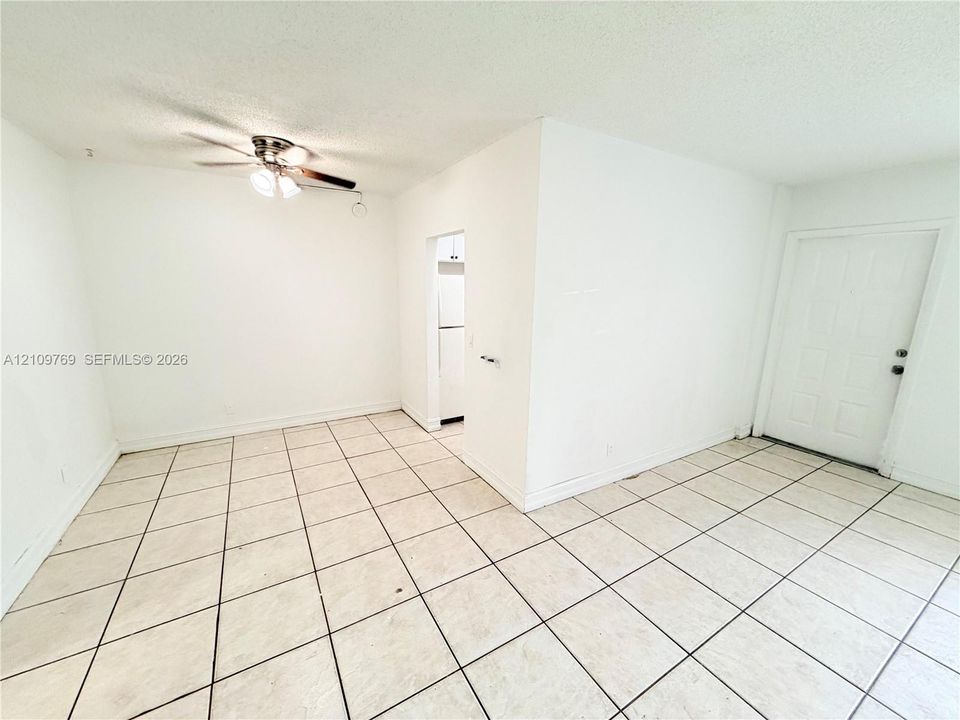 Interior space featuring neutral tile flooring, a multi-blade ceiling fan with integrated lighting, and a solid-panel entry door