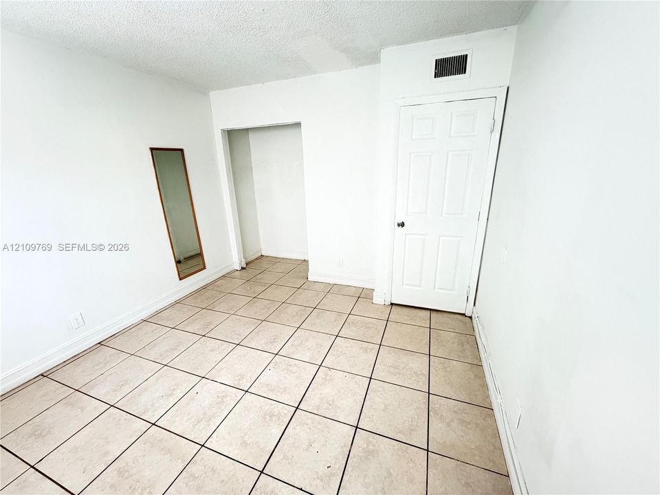 Interior room featuring tile flooring, a six-panel door, and a recessed alcove