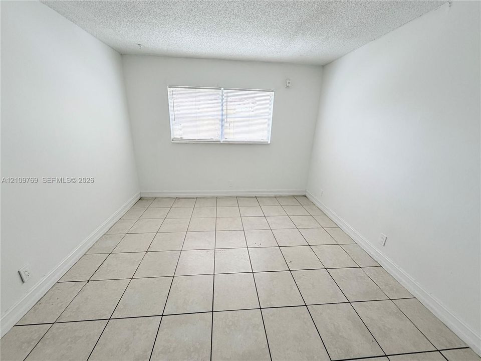 Room featuring ceramic tile flooring, neutral wall tones, and a window with horizontal blinds
