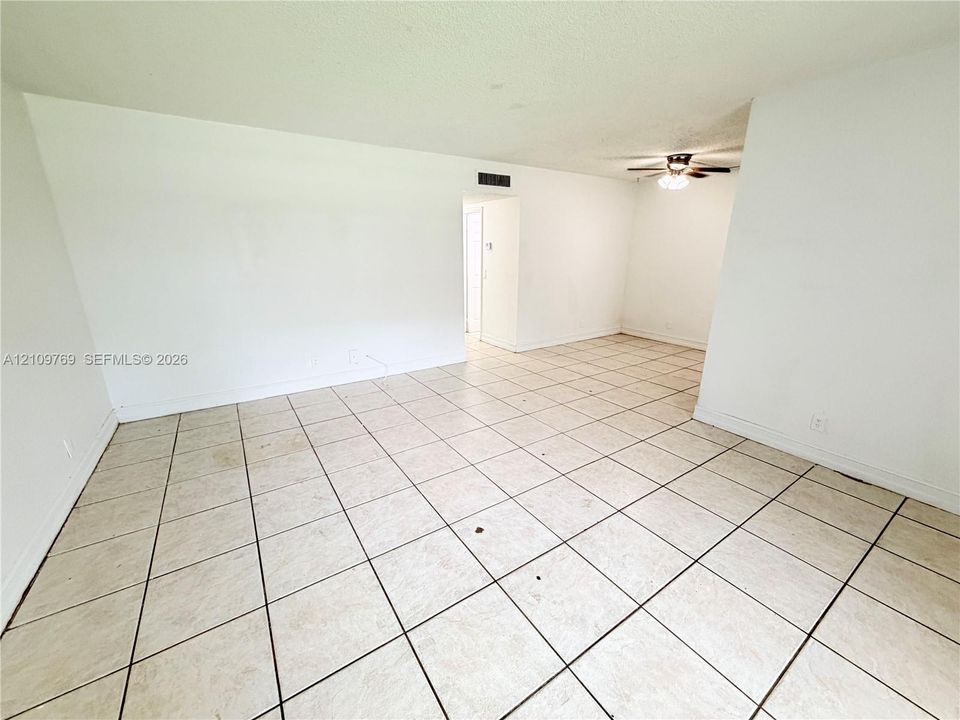 Spacious interior featuring neutral ceramic tile flooring and a ceiling-mounted light fixture with fan