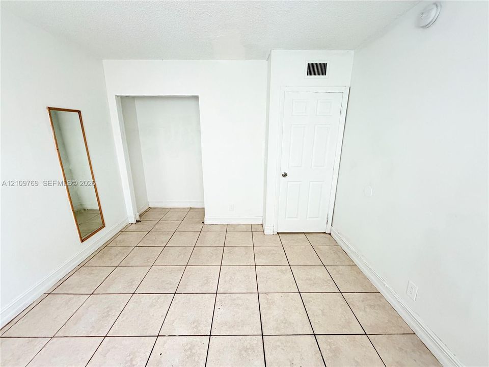 Neutral-toned tile flooring, recessed storage alcove, and a six-panel interior door
