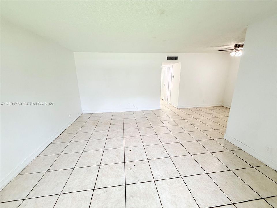 Neutral-toned square tile flooring with contrasting grout, white walls, and a ceiling-mounted light fixture