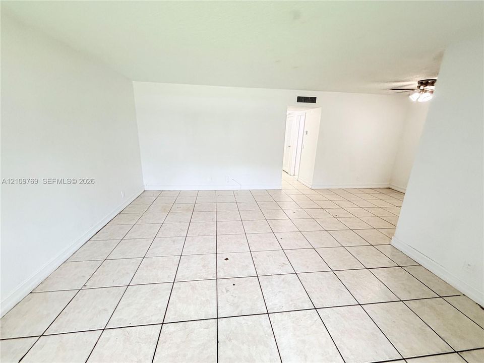 Open interior featuring large-format neutral tile flooring, smooth white walls, and a ceiling-mounted light fixture