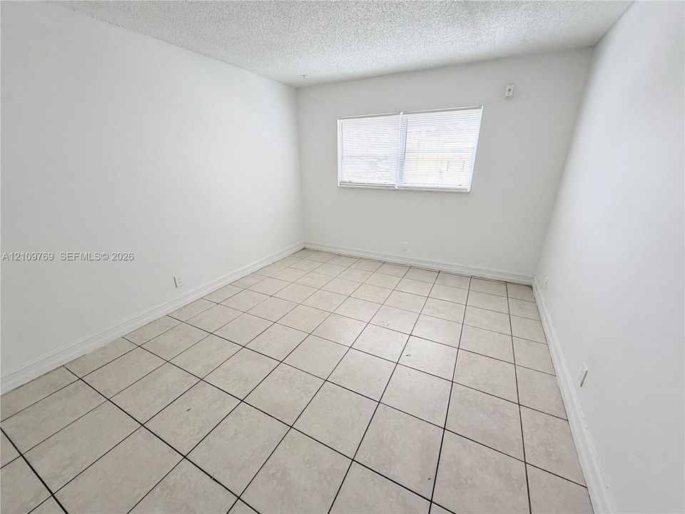 Interior room featuring large-format ceramic tile flooring, neutral wall finishes, and a window with horizontal blinds