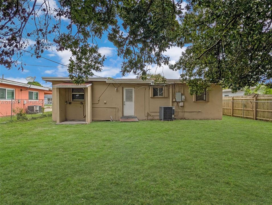 Backyard featuring a grass lawn, wooden perimeter fencing, and mature overhead tree canopy
