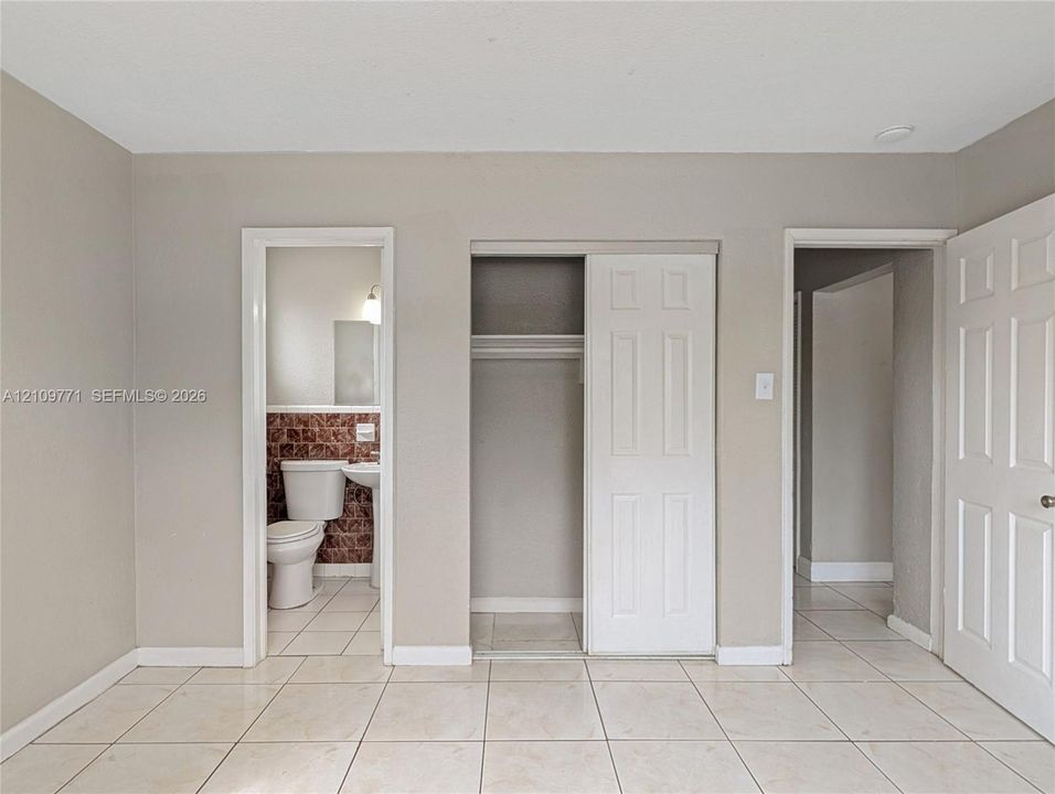 Neutral wall tones, ceramic tile flooring, built-in closet with sliding panel doors, and six-panel interior doors
