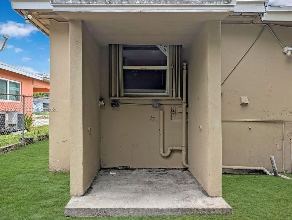 Covered concrete patio featuring a stucco exterior finish and single-pane window
