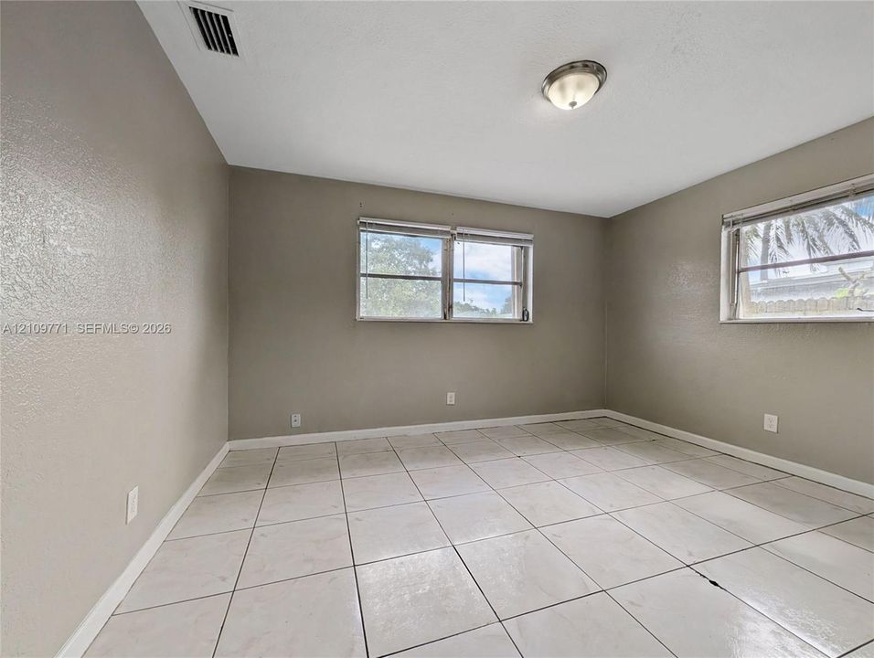 Interior space featuring light-colored tile flooring, neutral wall paint, two dual-pane windows, and a central ceiling-mounted light fixture