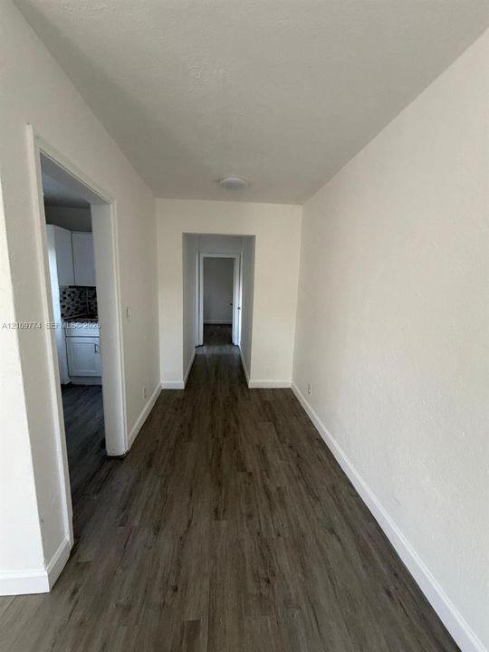 Hallway featuring neutral wall finishes and wood-finish flooring