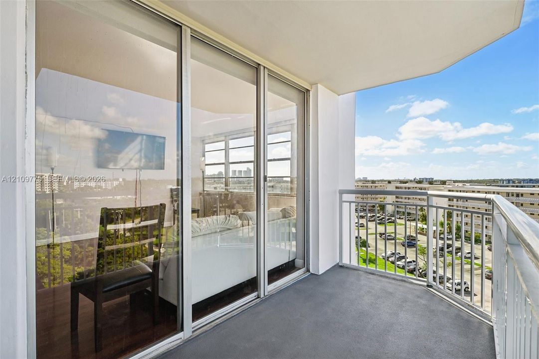 Covered private balcony featuring aluminum railings, floor-to-ceiling sliding glass doors, and solid surface flooring
