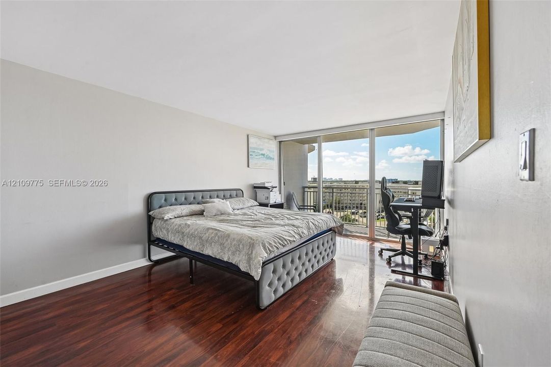 Wood-finish flooring, full-height sliding glass doors, and an outdoor balcony with exterior railing