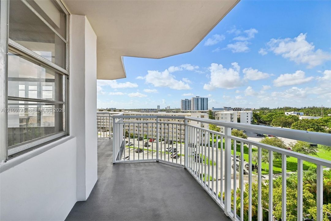 Covered balcony featuring white metal railings, concrete flooring, and sliding glass entry doors