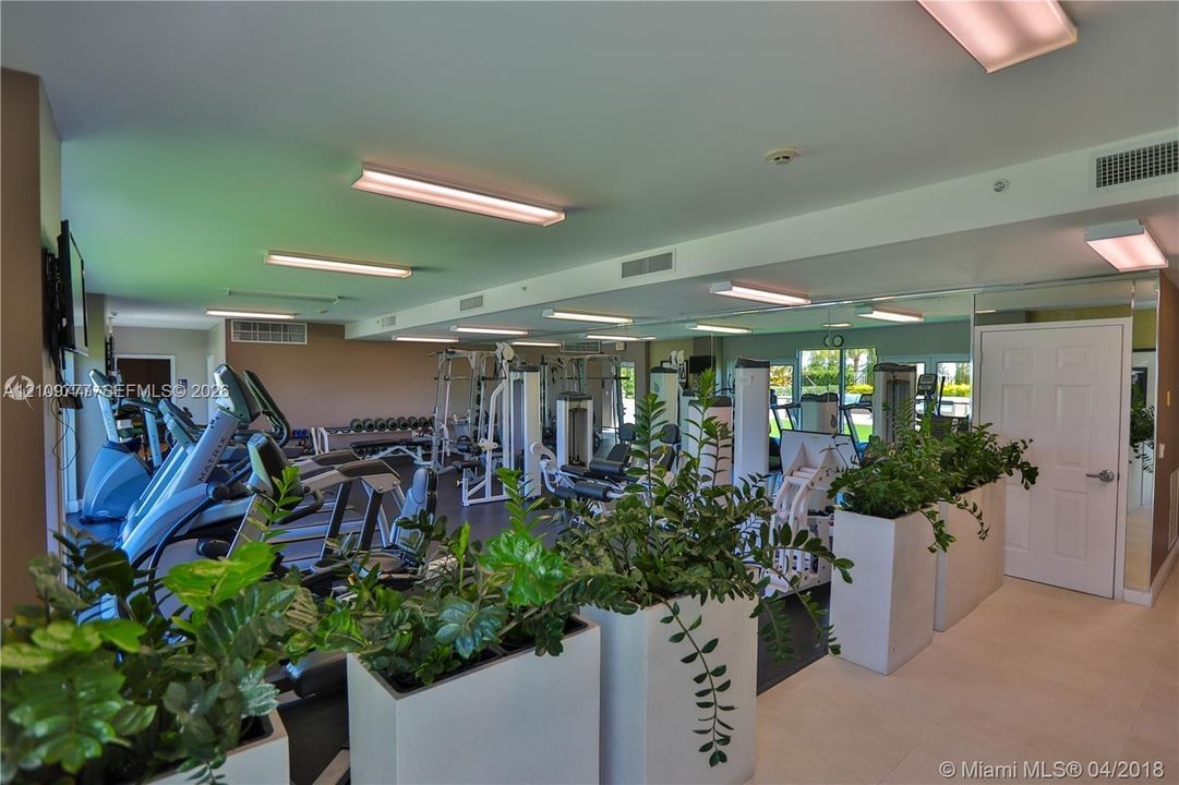 Fitness facility featuring full-length wall mirrors, recessed linear lighting, and large-format tile flooring