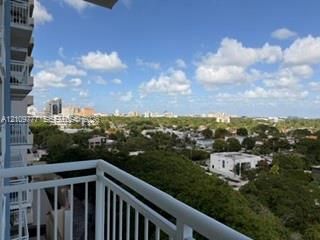 Private balcony with white metal railings, overlooking an expansive landscape of mature trees and surrounding city skyline