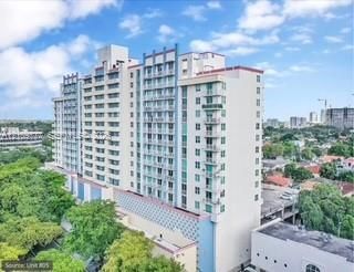 High-rise residential exterior featuring a multi-story facade, structured grid of private balconies, patterned architectural paneling, and integrated parking facility