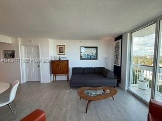 Living area featuring wood-finish flooring, floor-to-ceiling sliding glass doors, and a private balcony