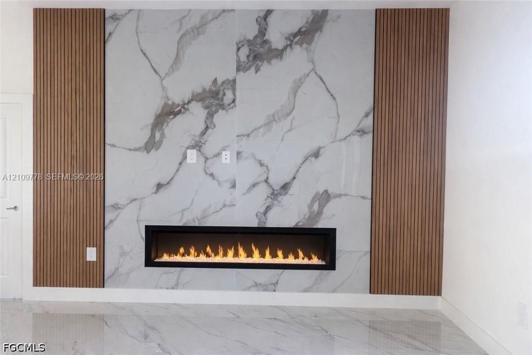 Floor-to-ceiling stone-finish hearth with a linear electric fireplace, flanked by vertical wood-slat accent wall panels